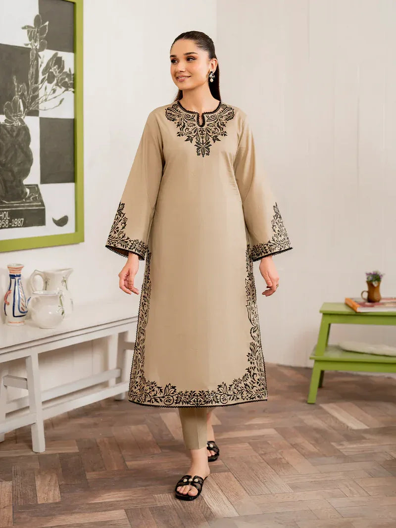 Woman wearing a beige kurta with black embroidery in a room setting.