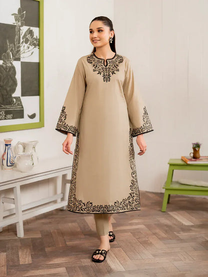 Woman wearing a beige kurta with black embroidery in a room setting.