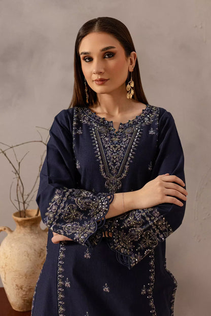Woman wearing a dark blue embroidered traditional outfit against a neutral background