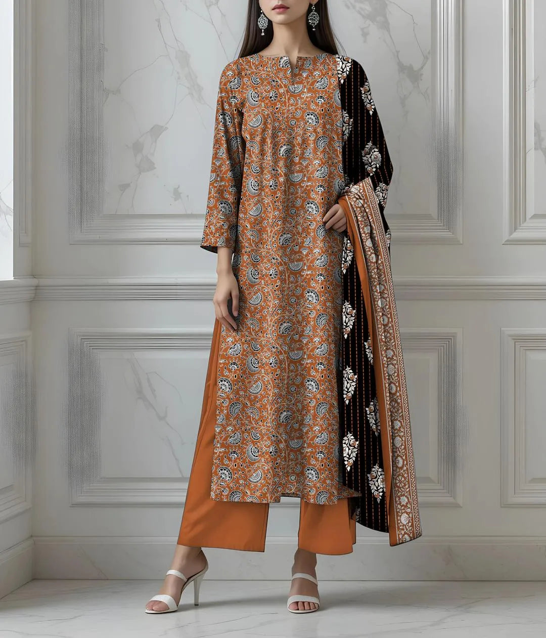 Woman wearing a patterned orange and black outfit with a matching dupatta against a white wall.