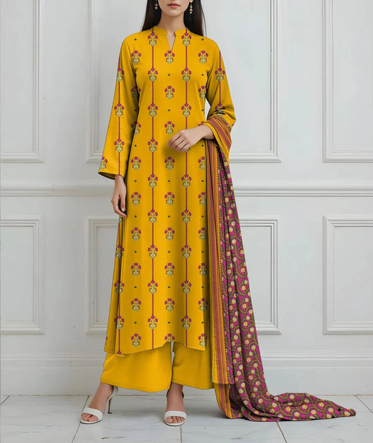 Woman wearing a yellow patterned outfit with a matching dupatta against a white paneled wall.