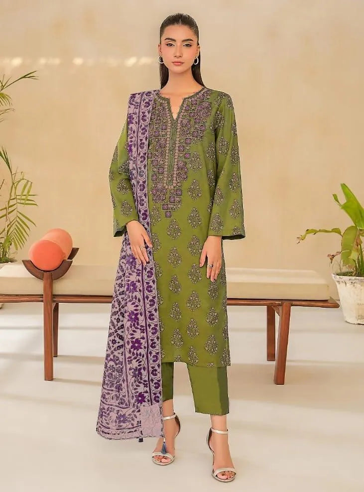 Woman wearing a green and purple traditional outfit in a minimalistic room.
