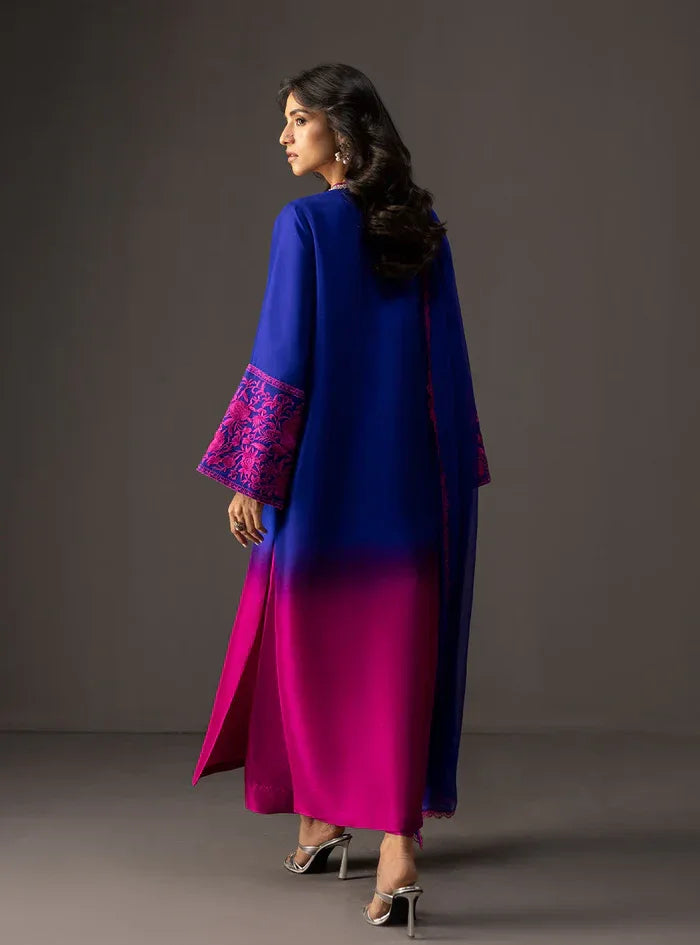 Woman wearing a blue and pink gradient dress with embroidered sleeves against a gray background