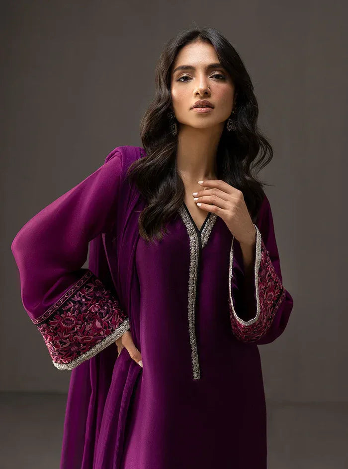 Woman wearing a purple dress with intricate designs on a dark background