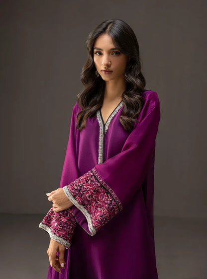 Woman wearing a purple dress with intricate patterns on a dark background