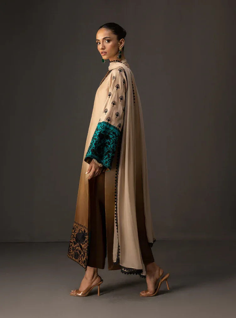 Woman wearing a long, patterned dress with a cape on a dark background