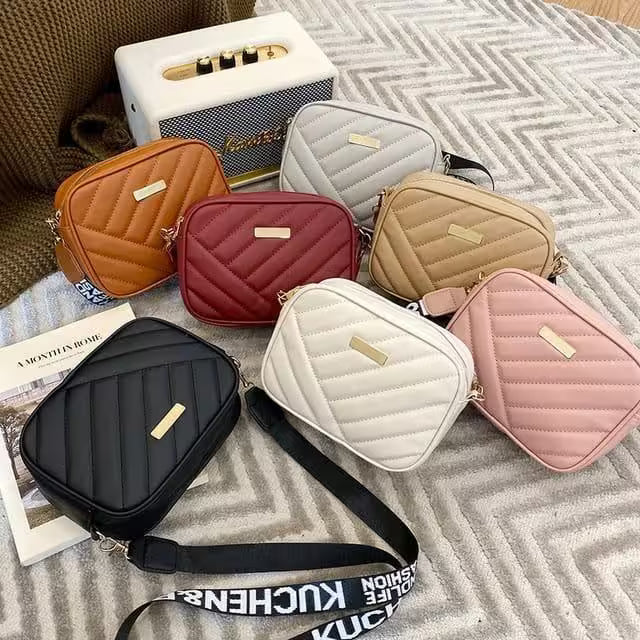 Collection of quilted handbags in various colors on a textured surface.