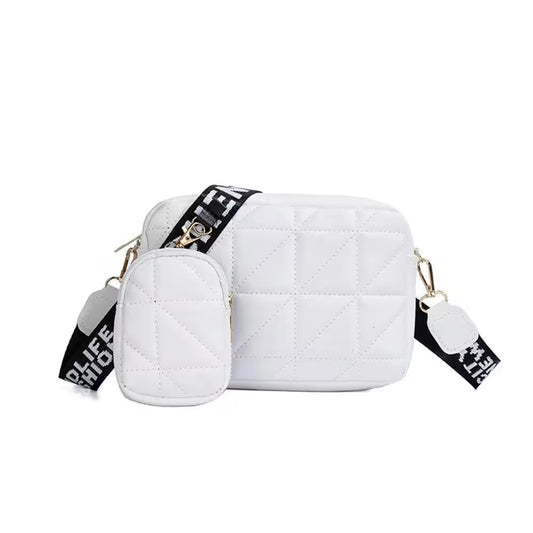 White quilted handbag with black and gold accents on a white background