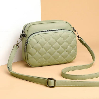 Quilted green handbag with a strap on a beige background