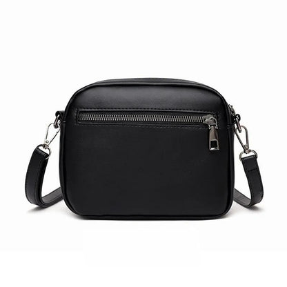Black crossbody bag with zippers on a white background