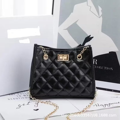 Black quilted handbag with gold chain on a magazine background
