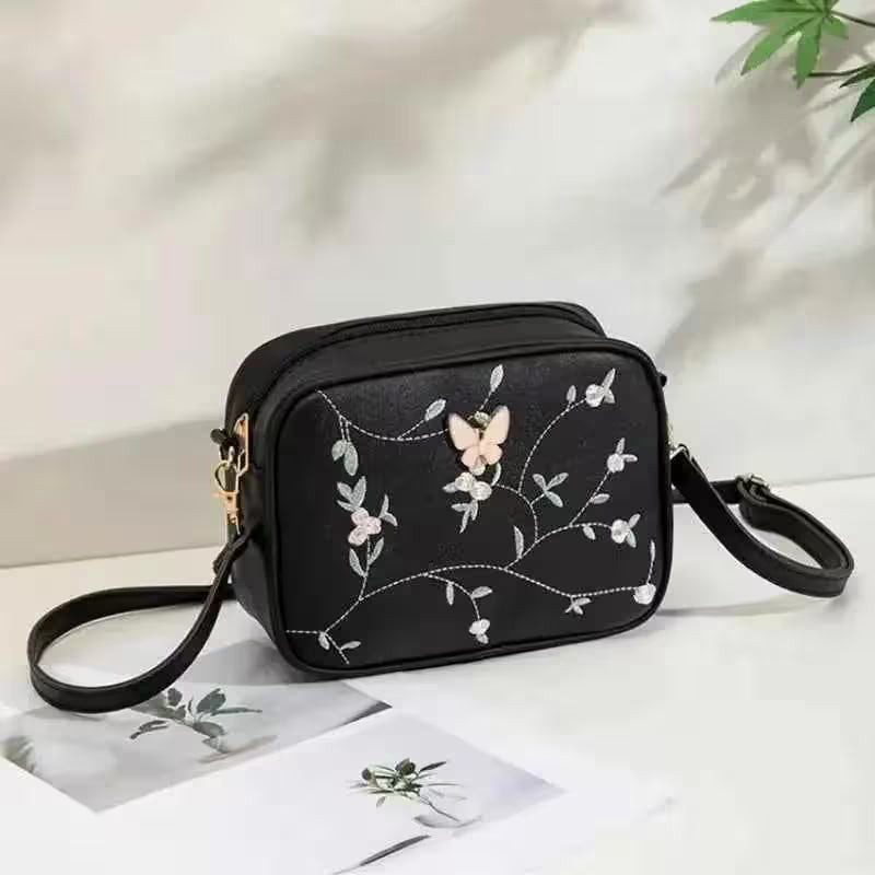 Black handbag with floral embroidery on a white surface