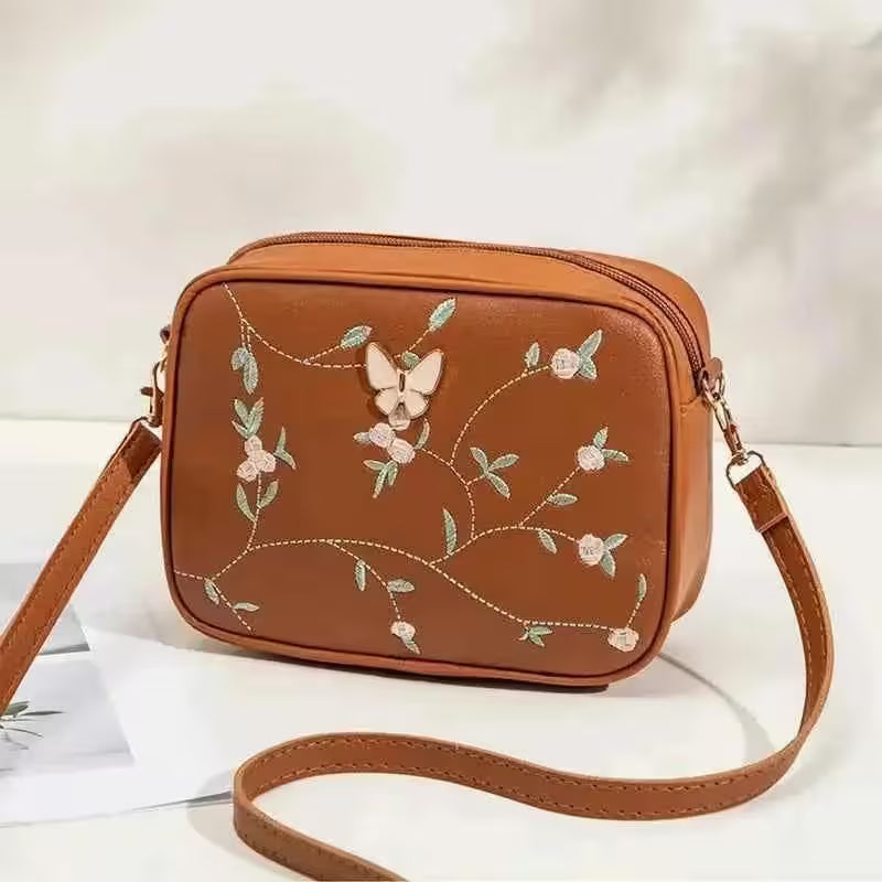 Brown crossbody bag with floral embroidery on a white background