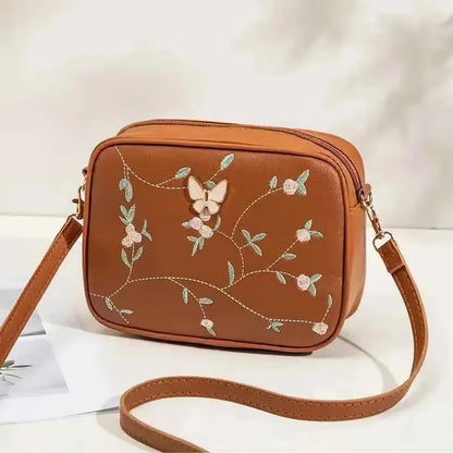 Brown crossbody bag with floral embroidery on a white background