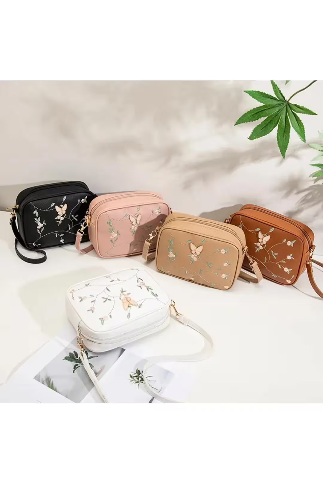 Five small handbags in different colors with floral embroidery on a light background.