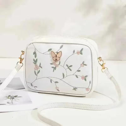 White handbag with butterfly and floral embroidery on a white background