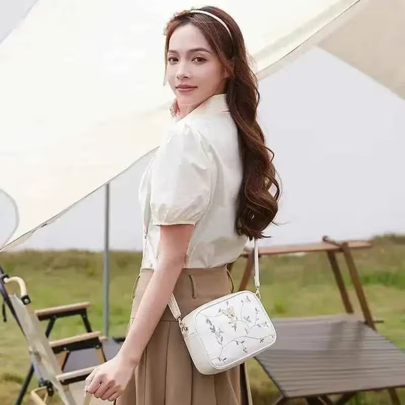 Woman holding a white handbag with floral patterns outdoors