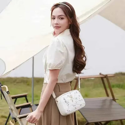Woman holding a white handbag with floral patterns outdoors