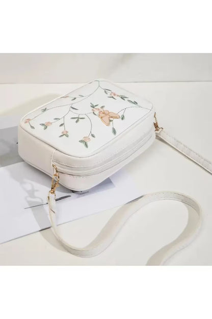White handbag with floral embroidery on a white background