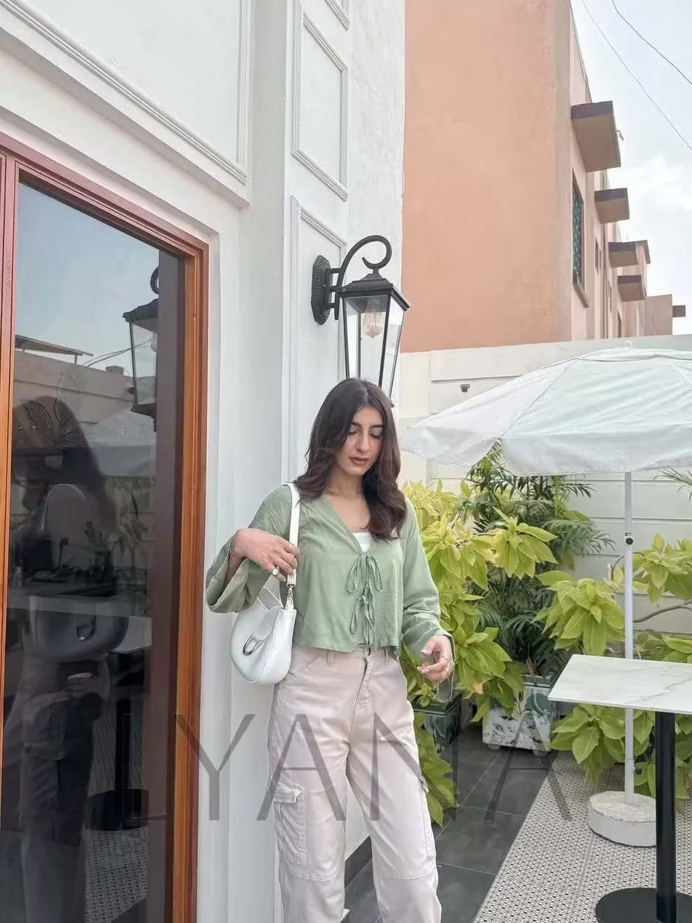 Woman standing on a rooftop patio with plants and a building in the background