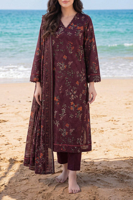 Woman wearing a burgundy floral dress on a beach with ocean in the background