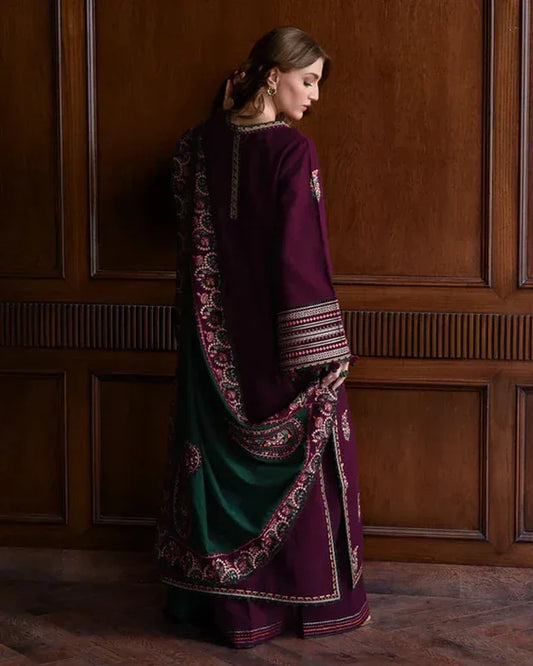 Woman wearing a traditional outfit with a dark purple and green sari against a wooden paneled wall.