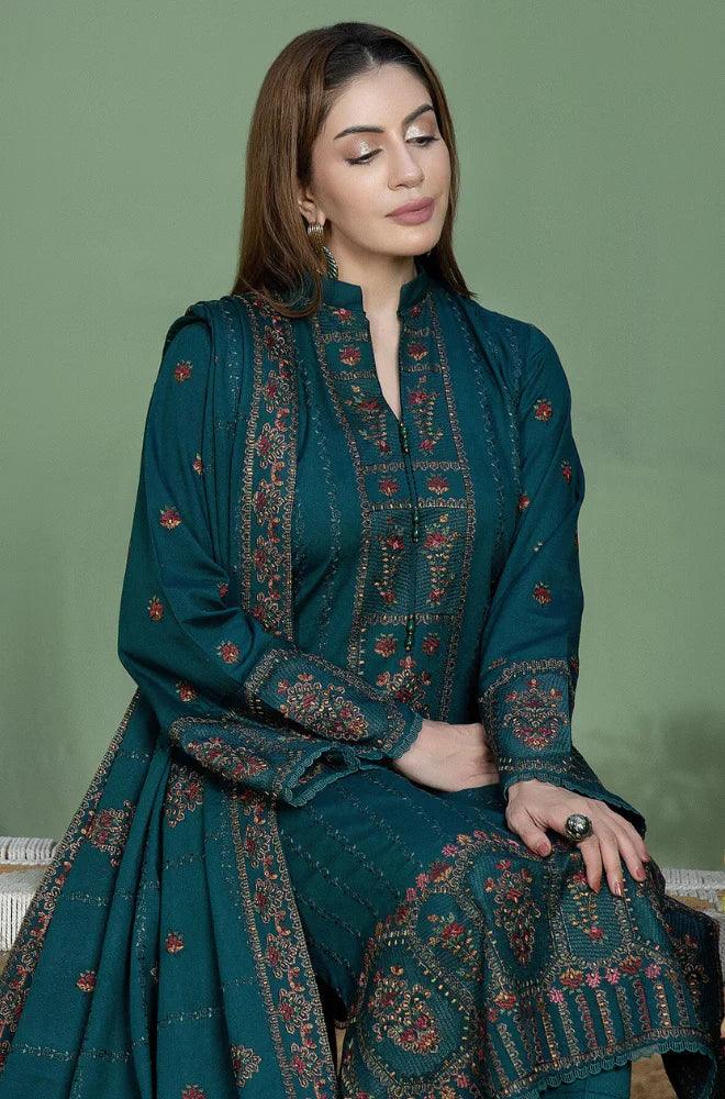 Woman wearing a teal embroidered traditional outfit against a green background