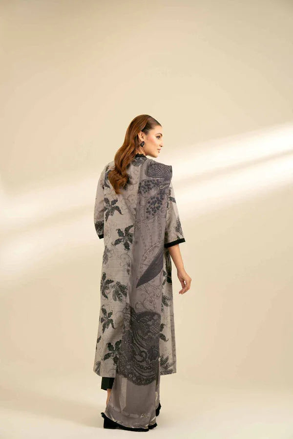 Woman wearing a long, patterned gray garment against a plain background