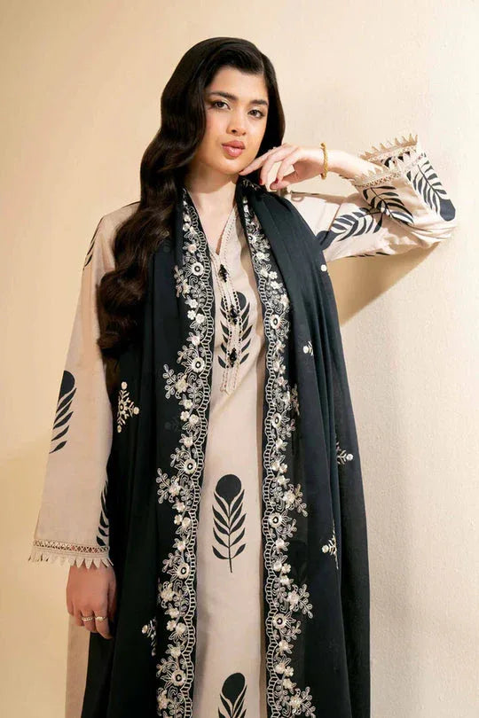 Woman wearing a black and white embroidered abaya against a beige background