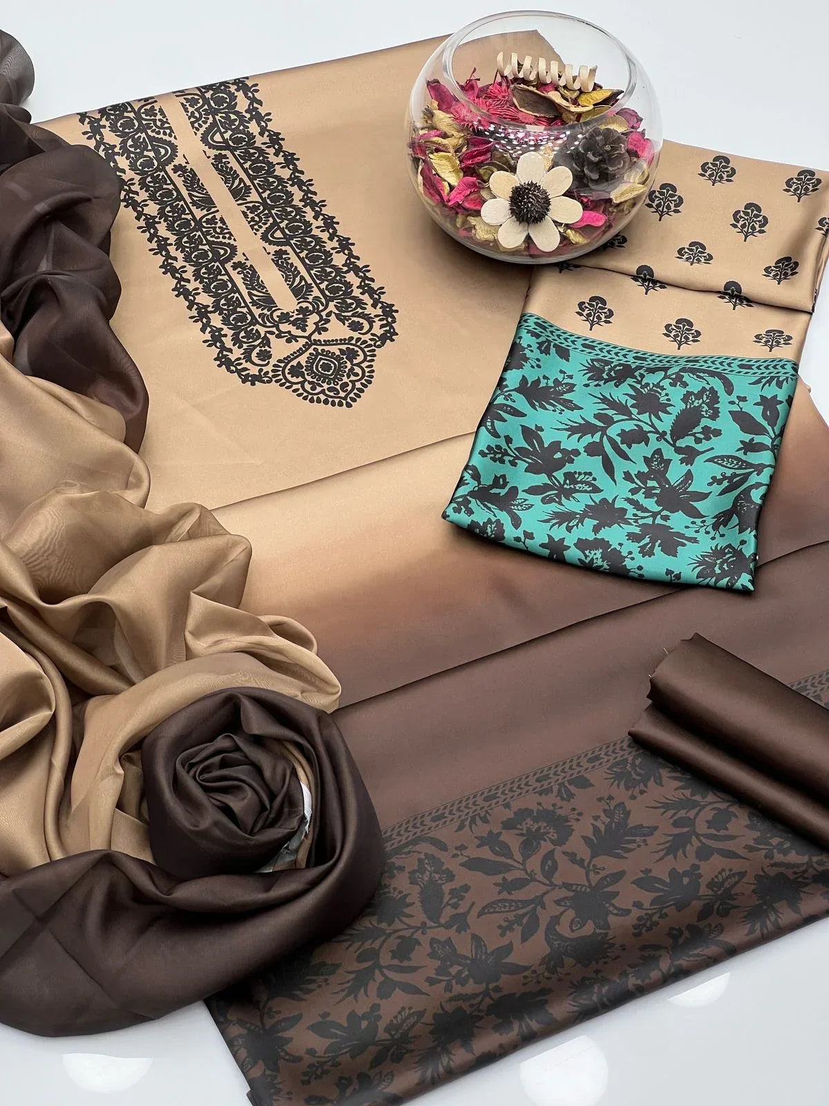 Decorative table setting with patterned tablecloth, napkins, and flowers on a white surface.