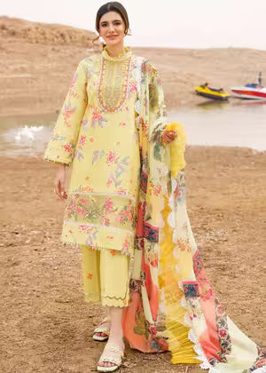 Woman in a yellow floral dress standing on a beach with a boat in the background