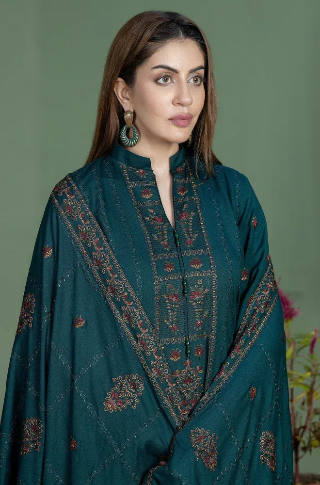 Woman wearing a teal embroidered traditional outfit against a green background