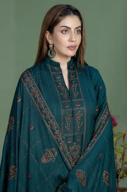 Woman wearing a teal embroidered traditional outfit against a green background