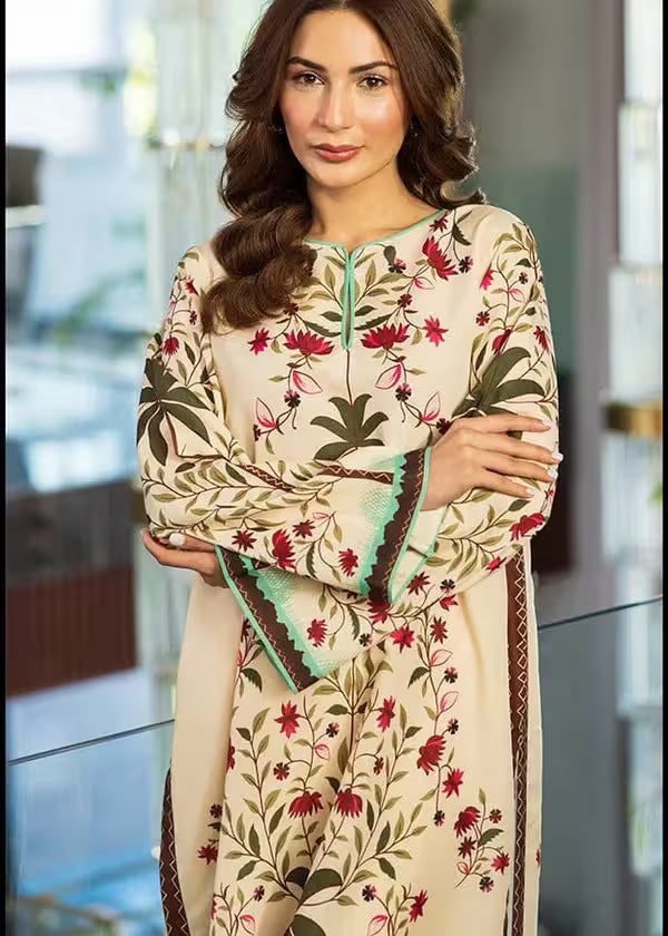 Woman wearing a cream-colored embroidered dress with floral patterns indoors.