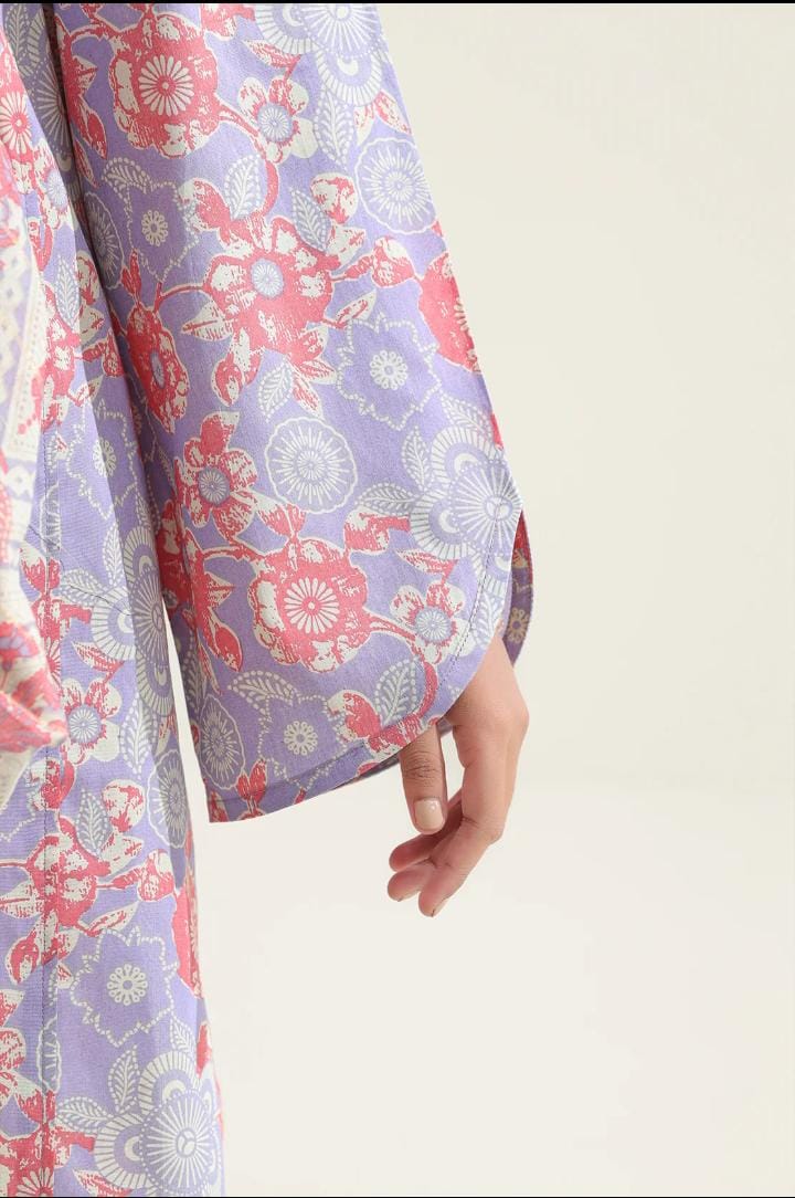 Close-up of a floral-patterned fabric with a hand holding it against a plain background