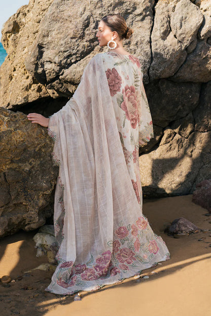 Woman in a floral dress standing against large rocks on a beach