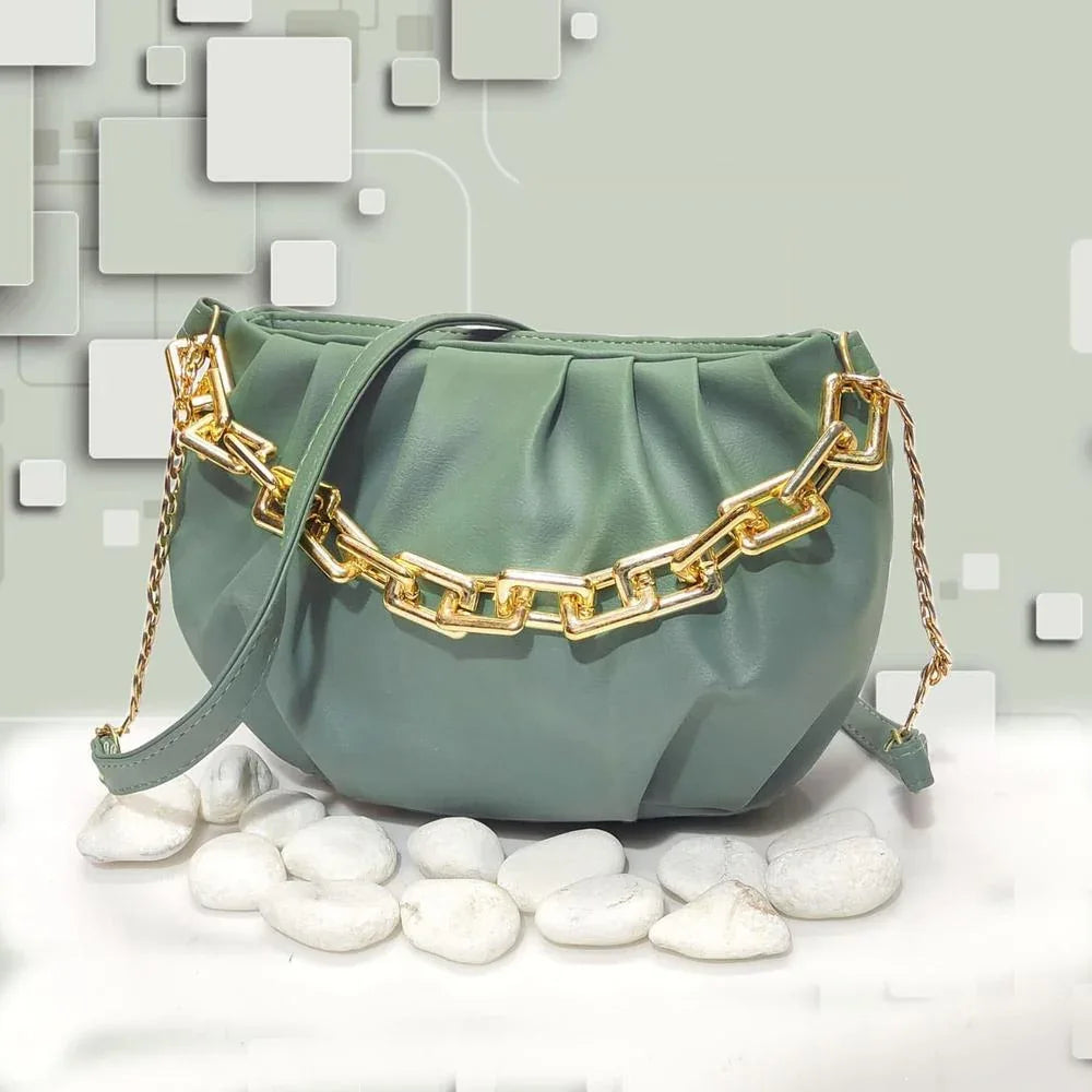 Green handbag with gold chain detail on a light gray background