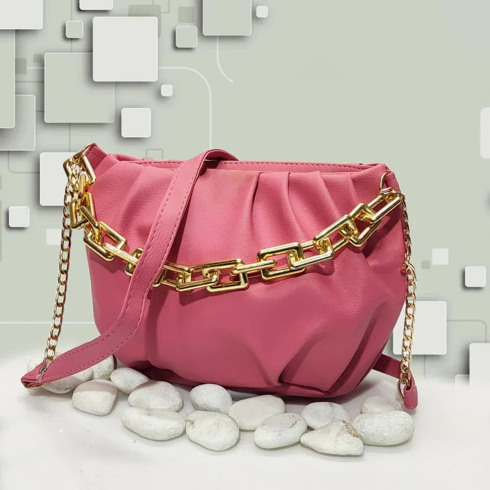 Pink handbag with gold chain strap on a light gray background