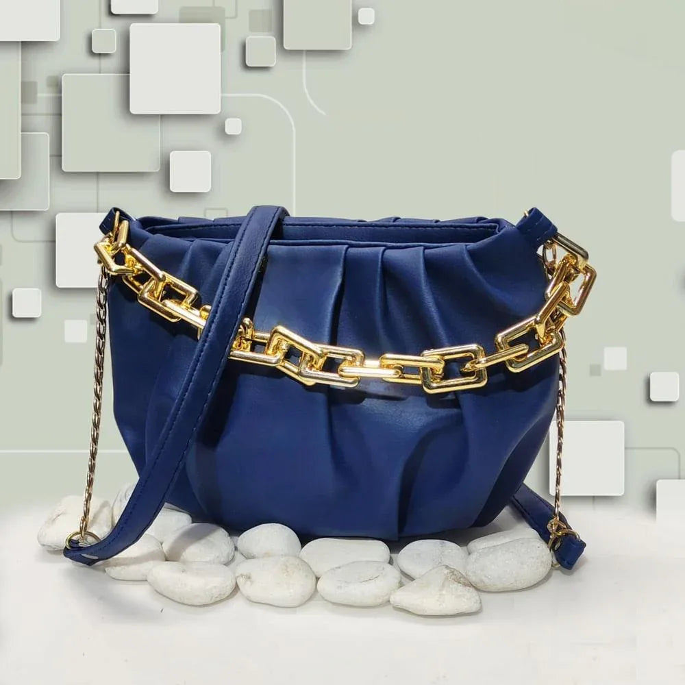 Blue handbag with gold chain detail on a textured surface