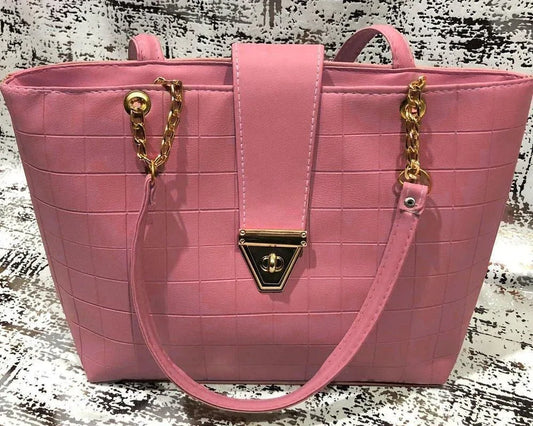 Pink handbag with gold accents on a textured surface