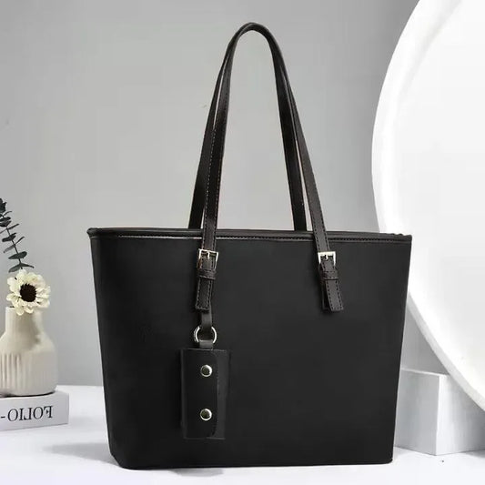 Black handbag with a strap on a light gray background