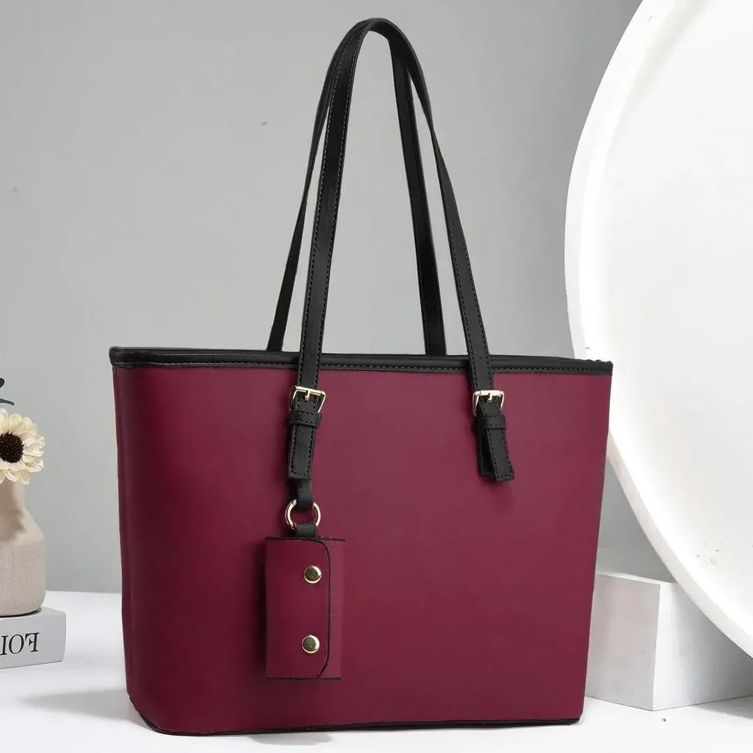 Maroon handbag with black handles on a gray background