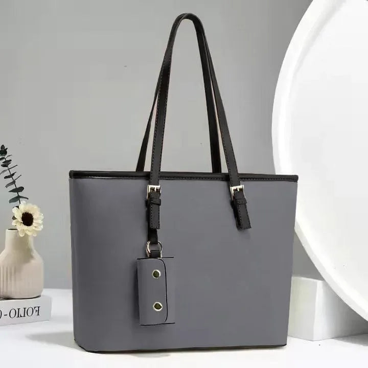 Gray handbag with black handle and strap on a light gray background