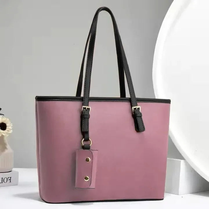 Pink handbag with black straps on a light gray background