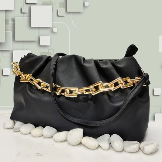Black handbag with gold chain detail on a light gray background