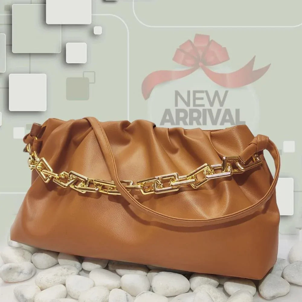 Brown handbag with gold chain detail on a light gray background with 'New Arrival' text.