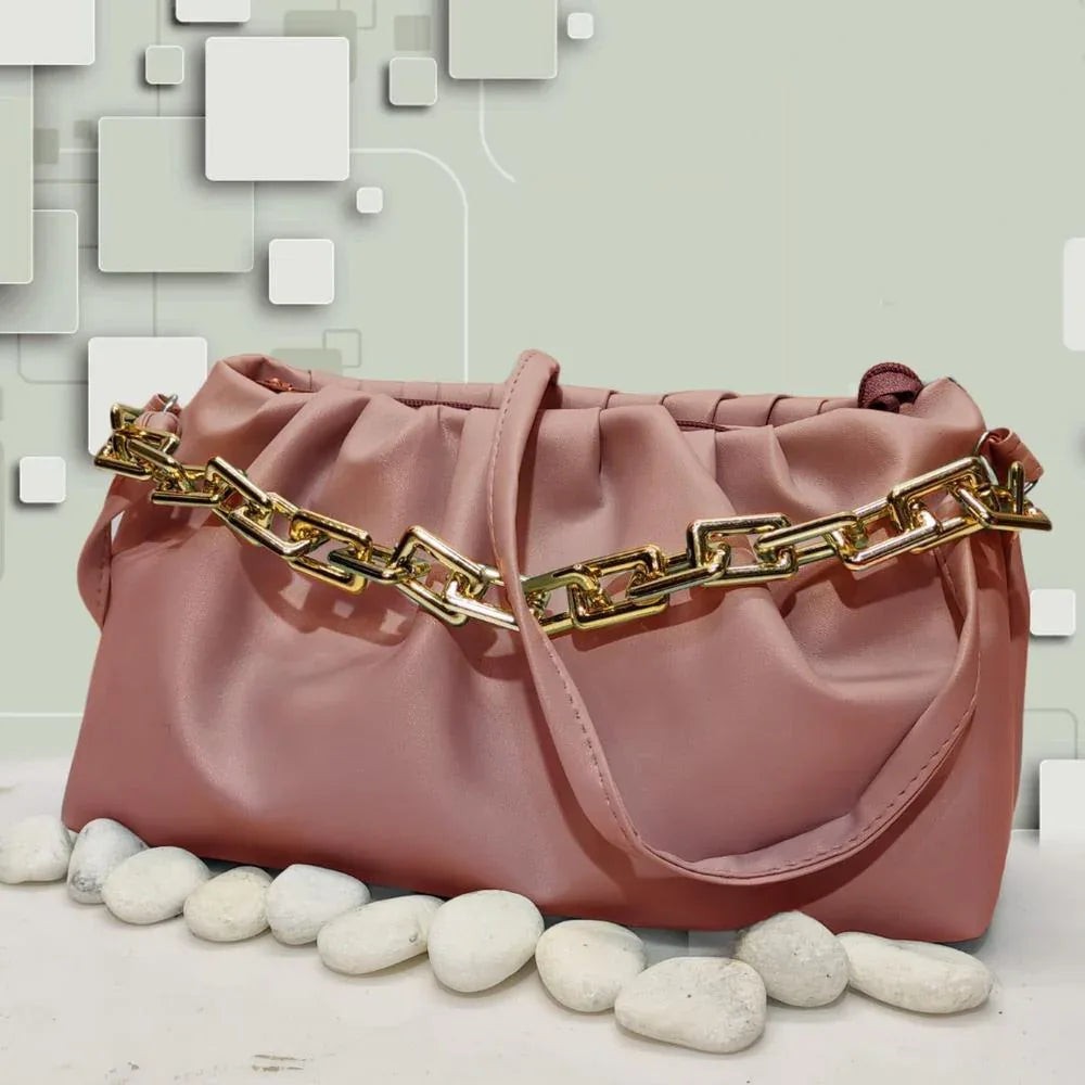 Pink handbag with gold chain detail on a light background