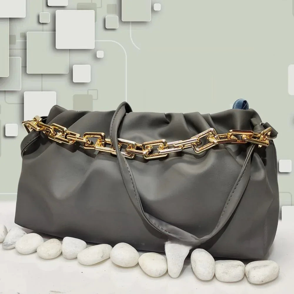 Gray handbag with gold chain detail on a textured surface