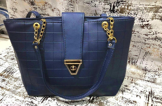 Blue handbag with gold accents on a textured surface