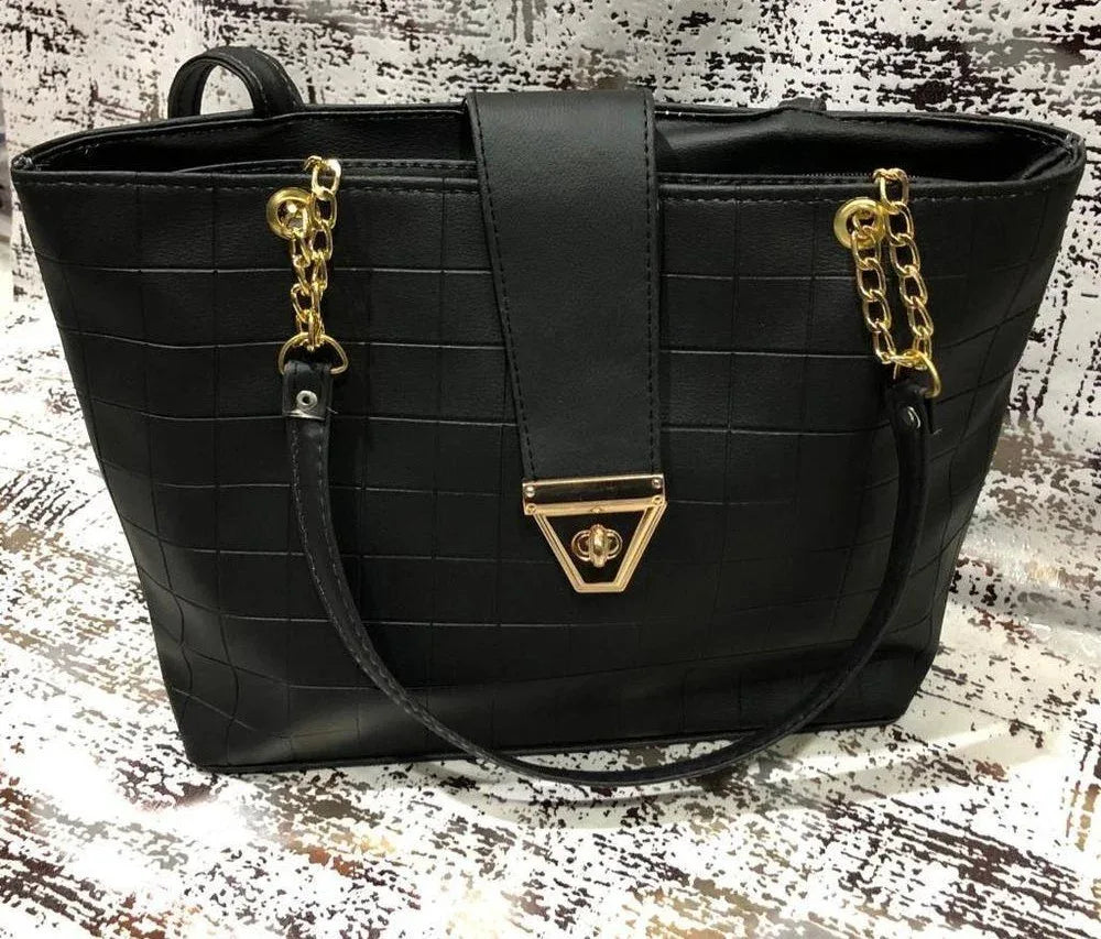 Black handbag with gold accents on a textured surface